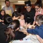 Familias y niños realizando los pinchos bajo la atenta mirada de Óscar Carbonell